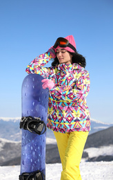 Photo of Young woman with snowboard on hill. Winter vacation