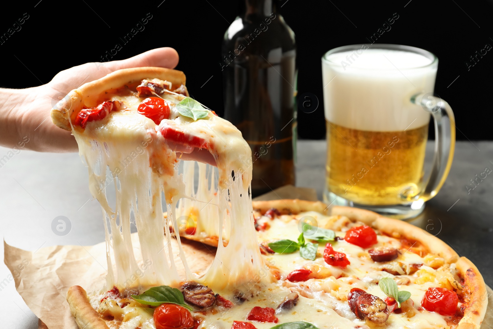 Photo of Woman holding slice of delicious hot pizza over table, closeup