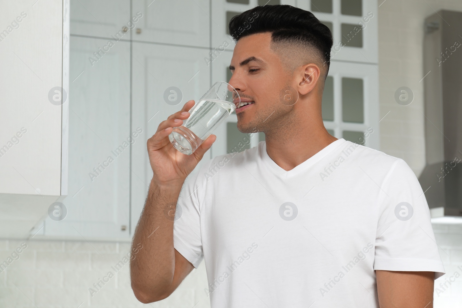 Photo of Man drinking tap water from glass in kitchen