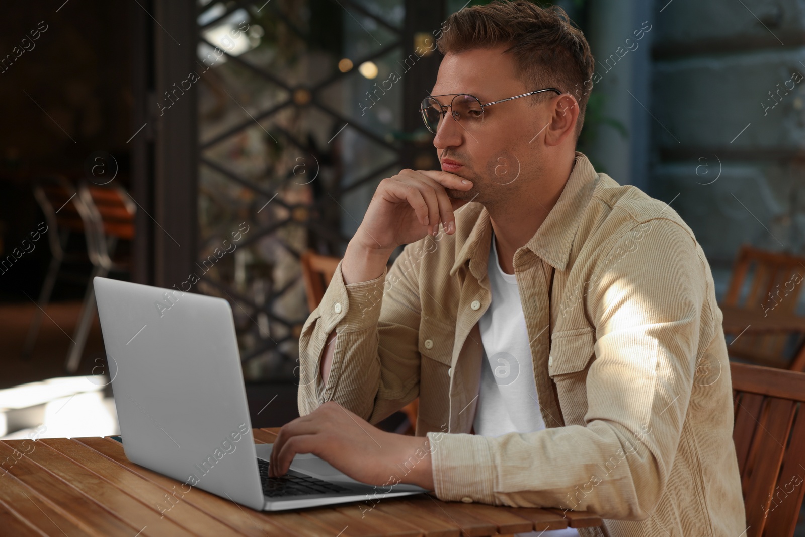 Photo of Handsome man working on laptop at table in outdoor cafe