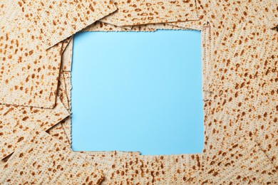 Photo of Frame of traditional matzos on light blue background, flat lay. Space for text