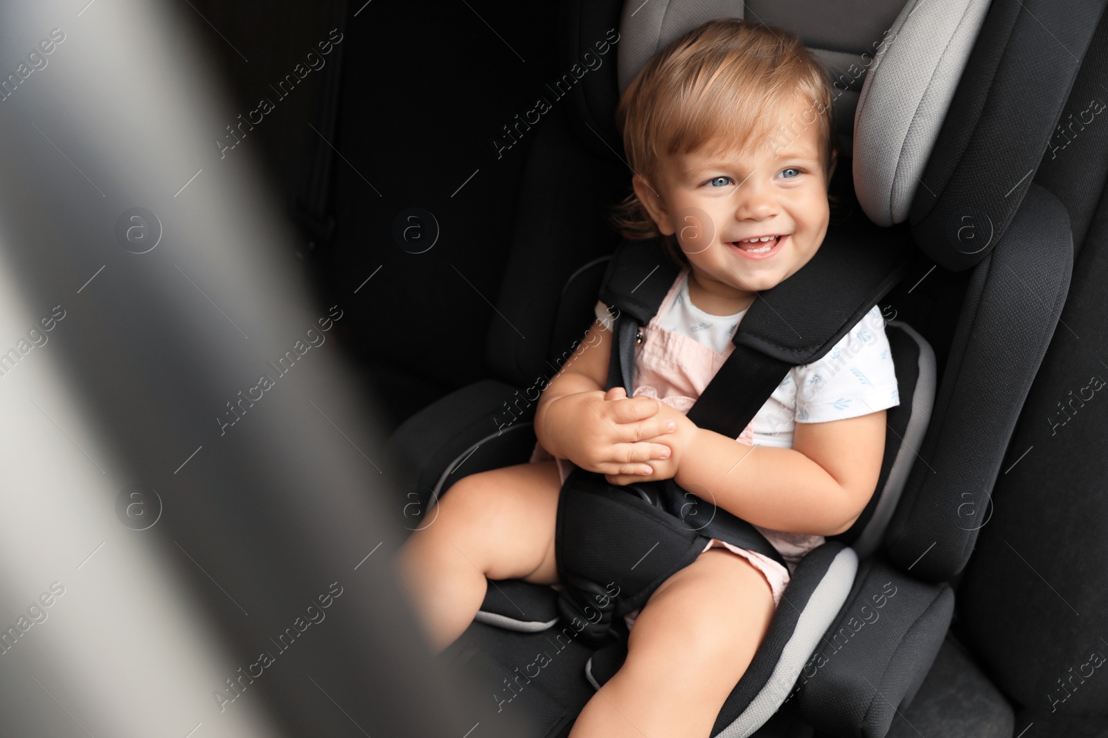 Photo of Cute little girl sitting in child safety seat inside car