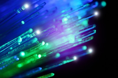 Image of Optical fiber strands transmitting green and blue light on black background, macro view