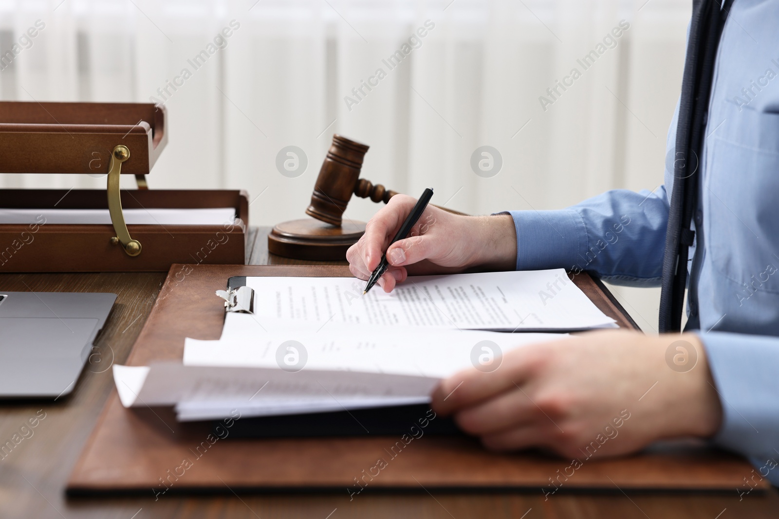 Photo of Lawyer working with documents at wooden table indoors, closeup