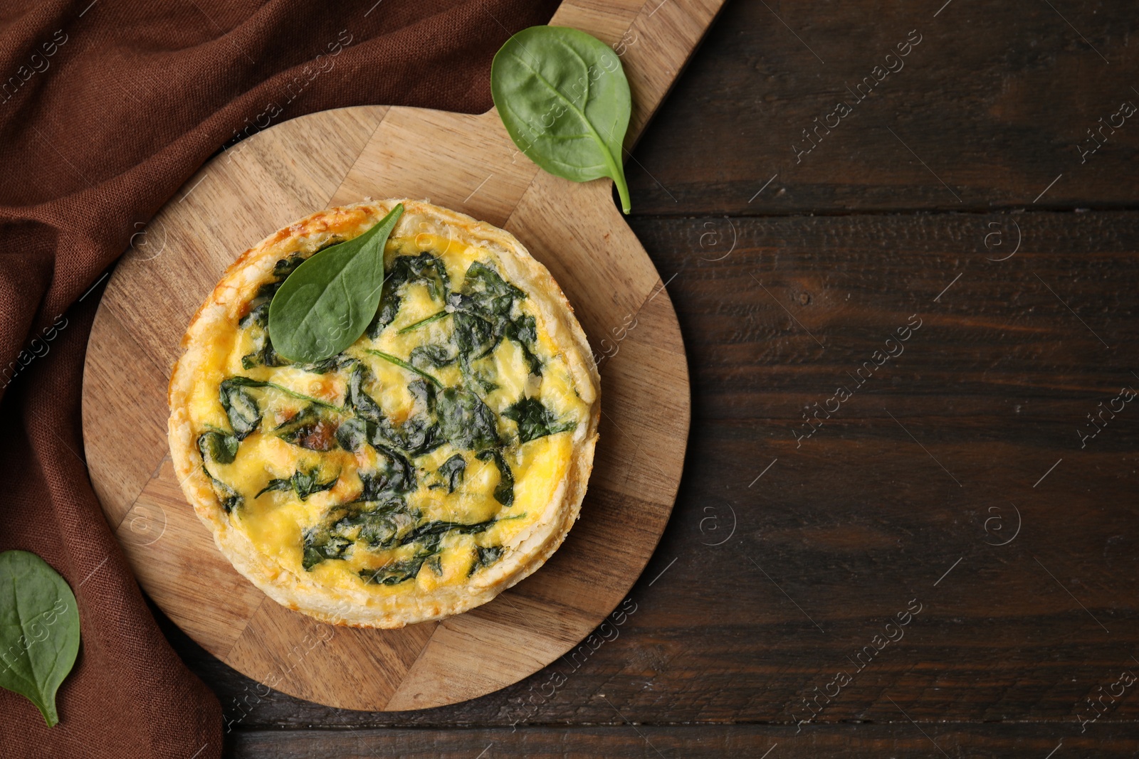 Photo of Delicious pie with spinach on wooden table, top view. Space for text