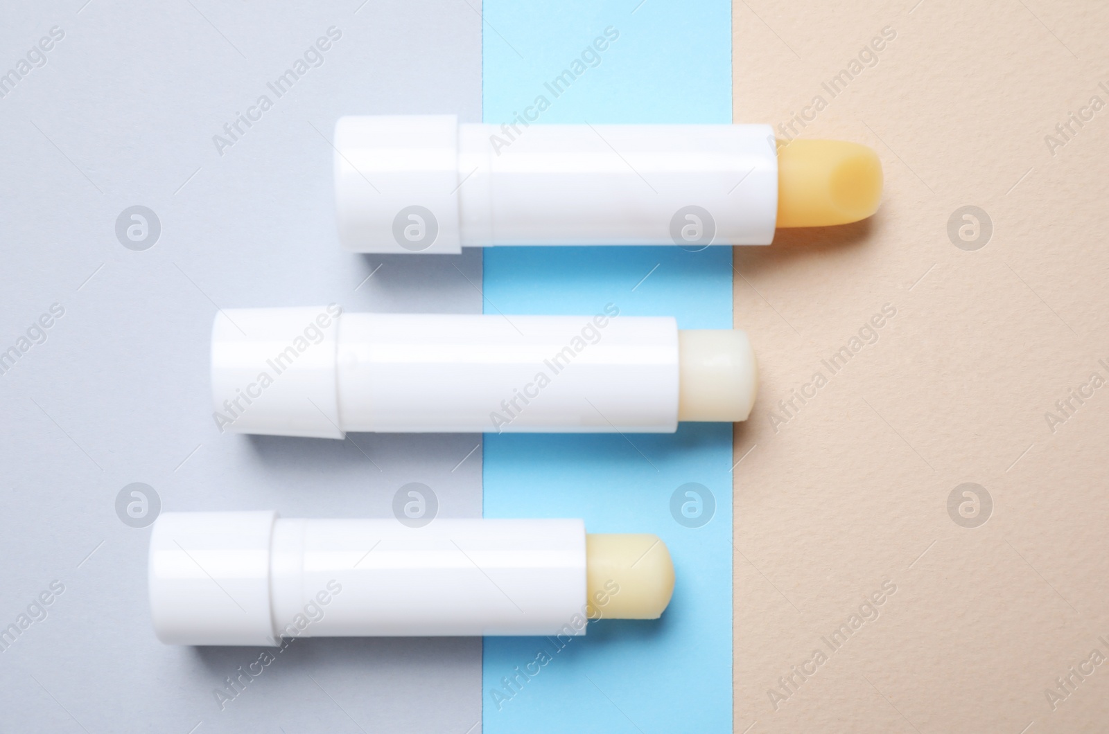 Photo of Hygienic lipsticks on color background, flat lay