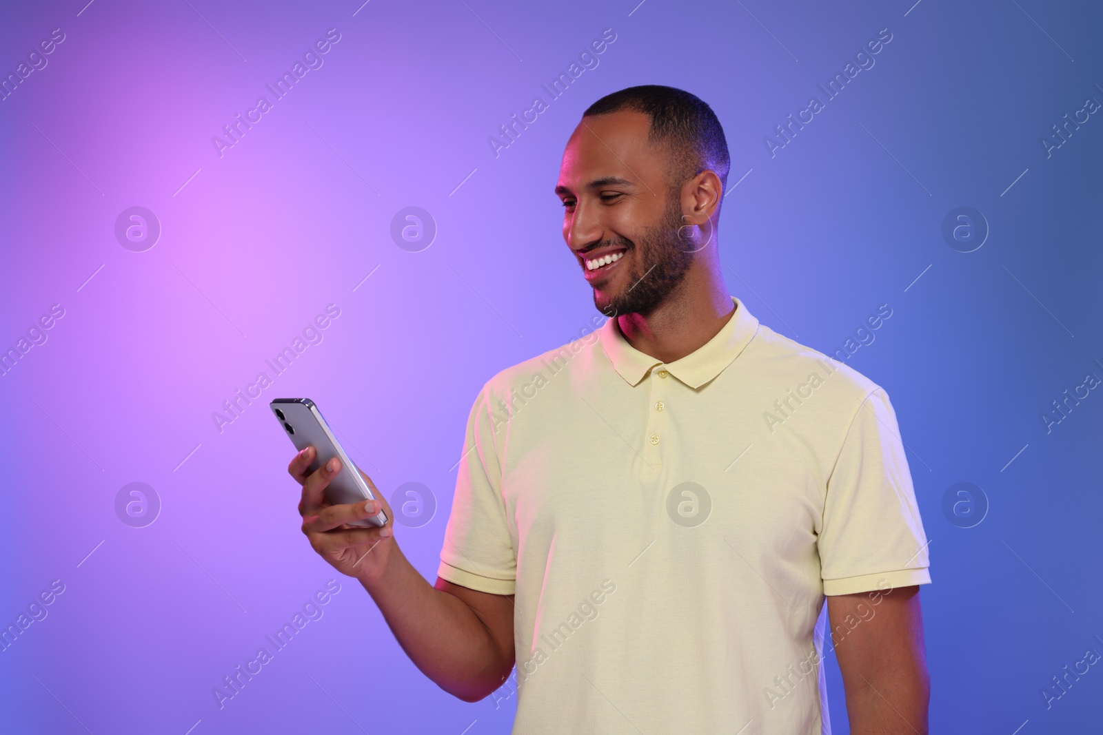 Photo of Happy man sending message via smartphone on color background