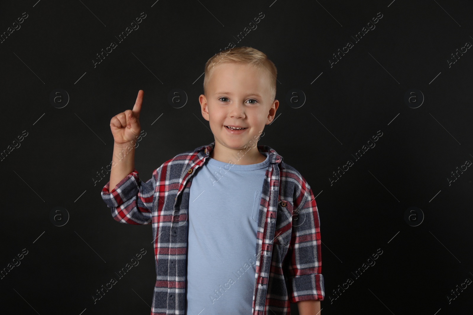 Photo of Emotional little boy on black background. Thinking about answer for question