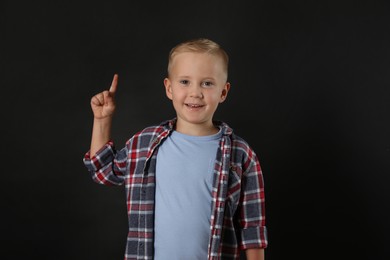 Photo of Emotional little boy on black background. Thinking about answer for question