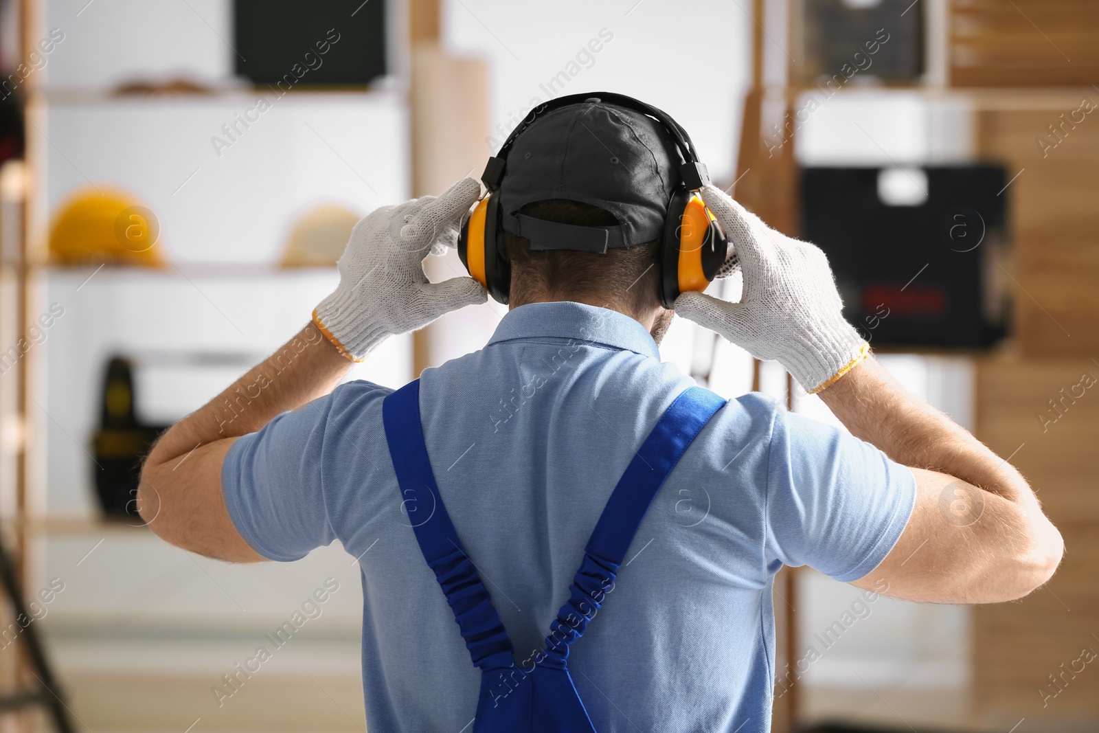 Photo of Worker wearing safety headphones indoors, back view. Hearing protection device