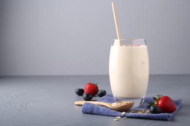 Photo of Tasty yogurt in glass, oats and berries on grey table, space for text