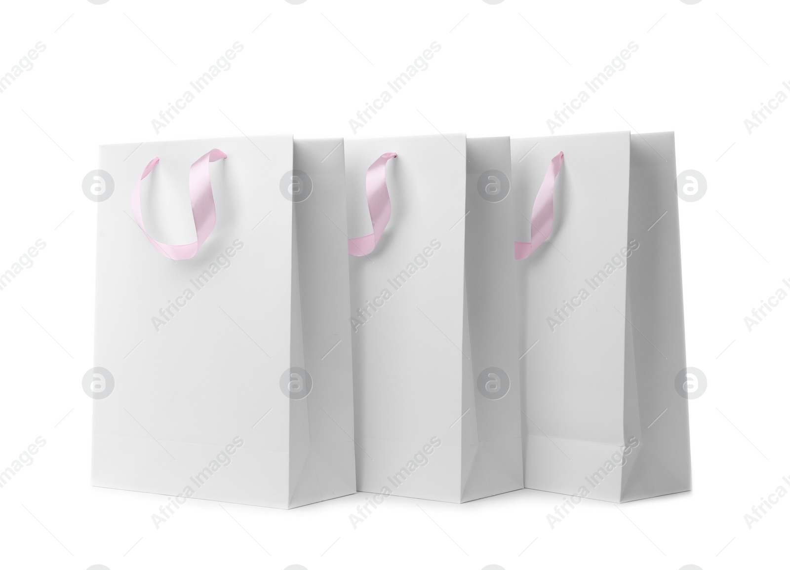 Photo of Paper shopping bags with ribbon handles on white background. Mockup for design