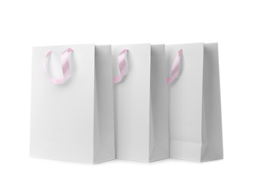 Photo of Paper shopping bags with ribbon handles on white background. Mockup for design