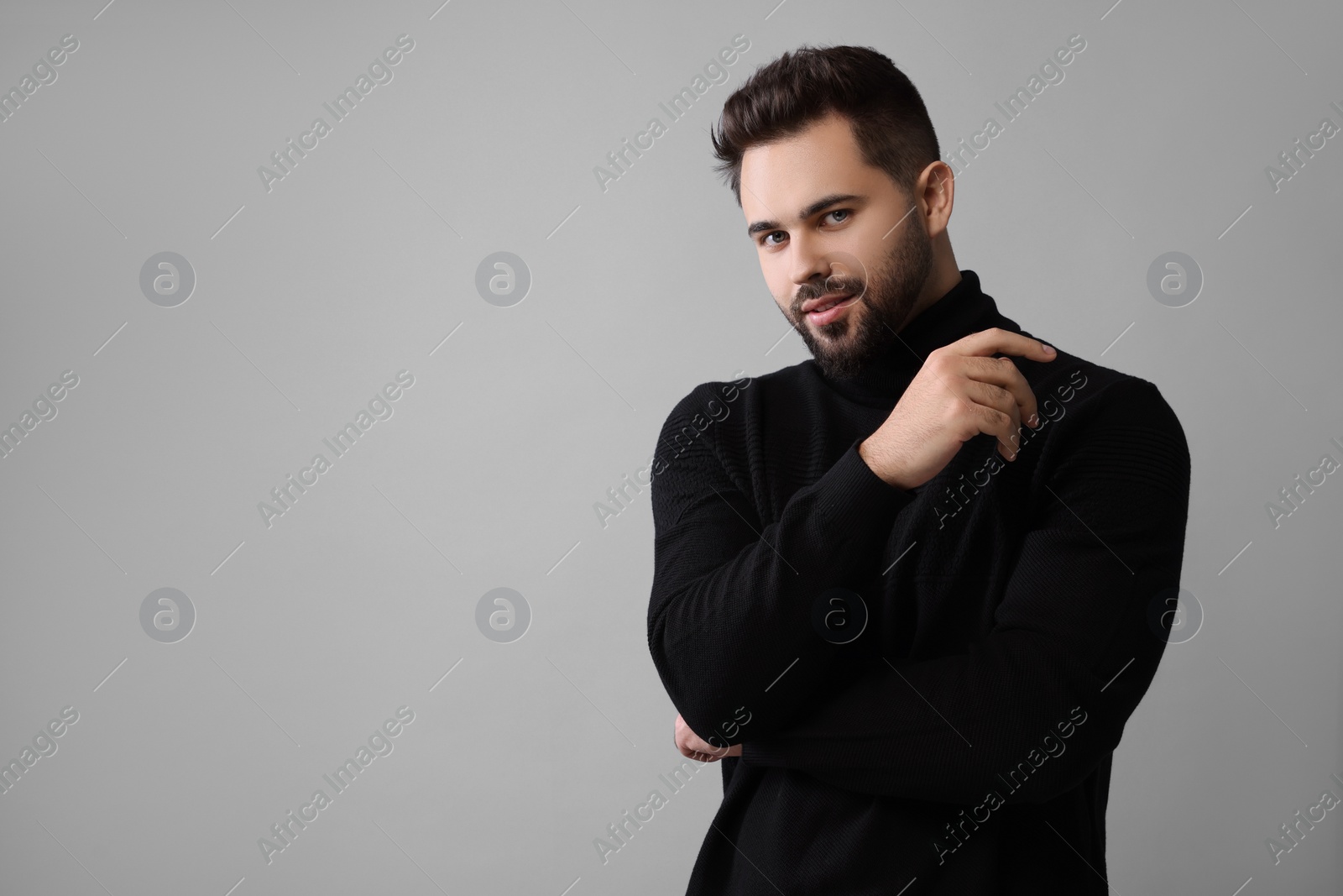 Photo of Handsome man in stylish black sweater on grey background, space for text