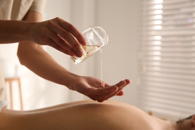 Photo of Young woman receiving back massage with oil in spa salon, closeup