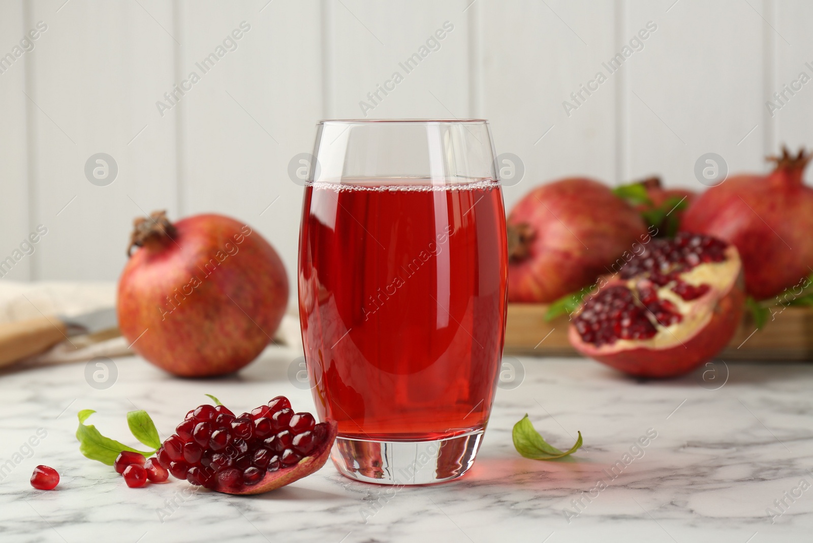 Photo of Tasty pomegranate juice in glass and fresh fruits on white marble table