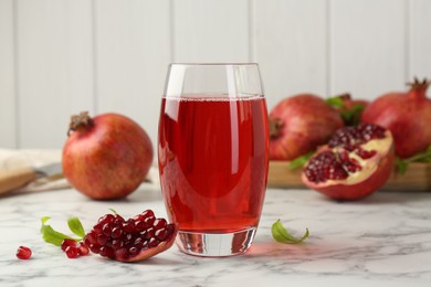 Photo of Tasty pomegranate juice in glass and fresh fruits on white marble table