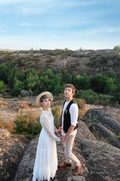 Photo of Happy newlyweds standing on rock outdoors