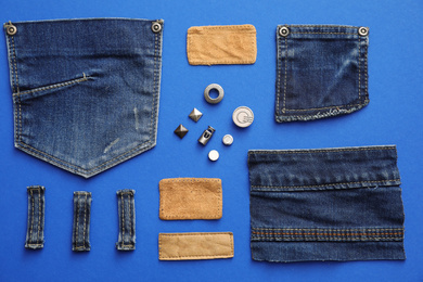 Flat lay composition with garment accessories and cutting details for jeans on blue background