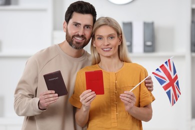 Immigration. Happy couple with passports and flag of United Kingdom indoors