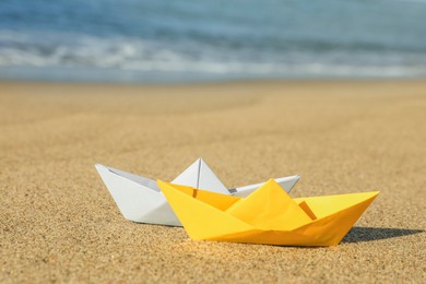 Photo of Color paper boats near sea on sandy beach