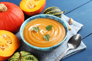 Photo of Delicious pumpkin soup served on blue wooden table