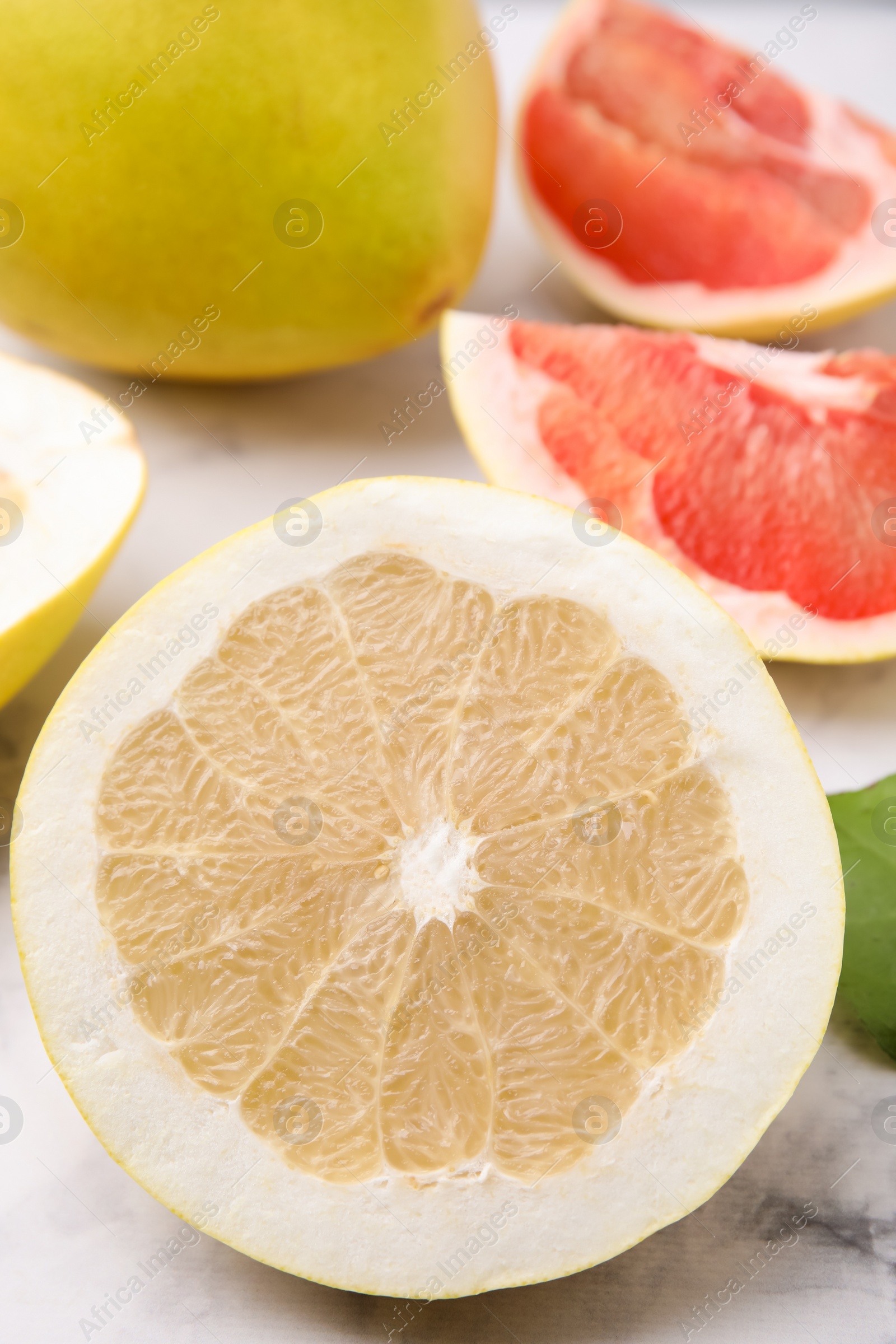 Photo of Different sorts of tasty pomelo fruits on white marble table, closeup