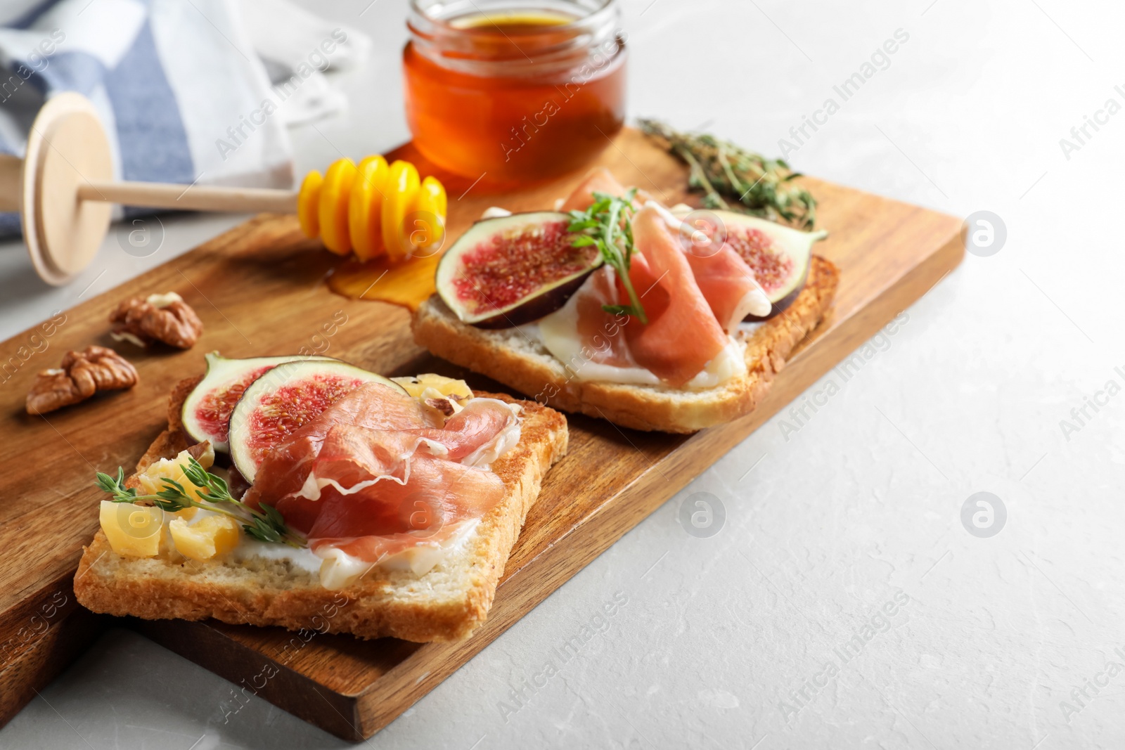 Photo of Delicious sandwiches with figs, proscuitto and cheese on light table, closeup