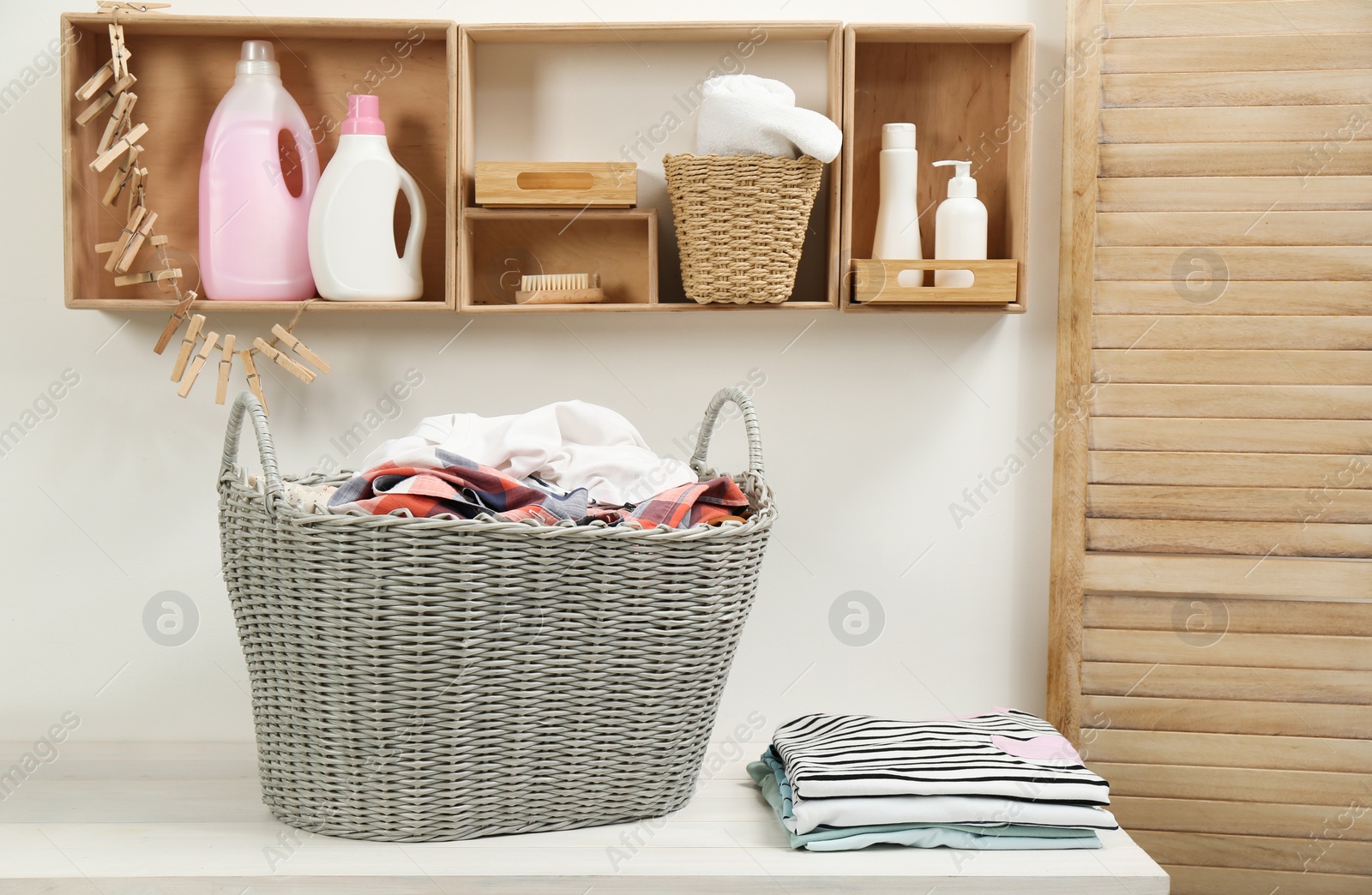 Photo of Wicker basket with dirty laundry on white table in bathroom