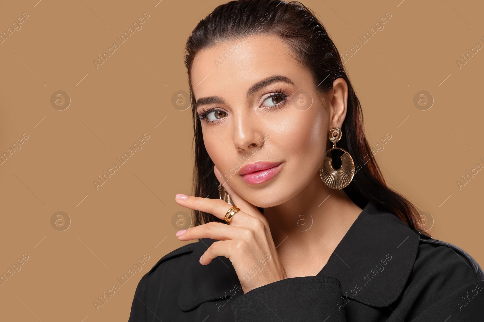 Photo of Portrait of young woman with beautiful makeup on light brown background