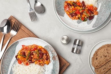 Photo of Chili con carne served with rice on gray table, flat lay