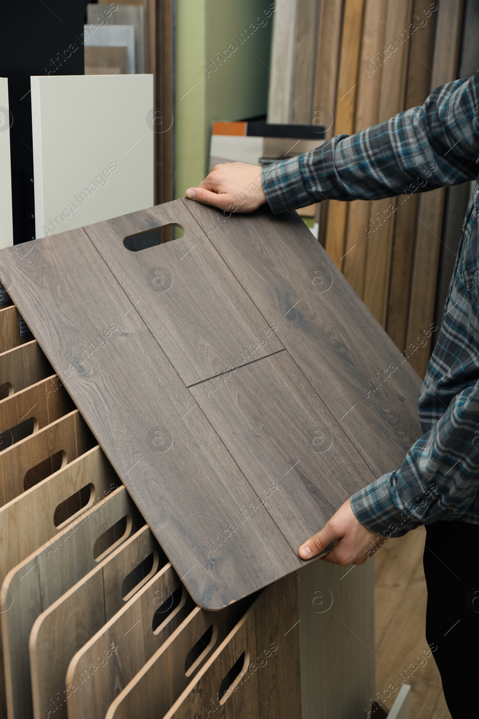 Photo of Man with sample of wooden flooring in shop, closeup