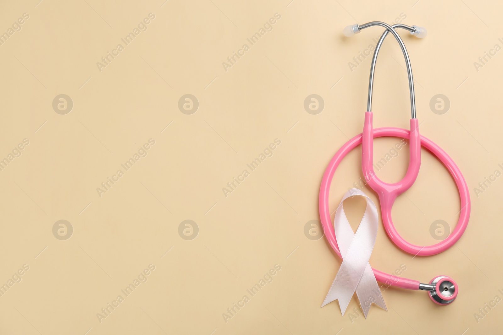 Photo of Pink ribbon and stethoscope on beige background, flat lay with space for text. Breast cancer concept