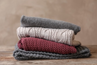 Photo of Stack of warm knitted clothes on table