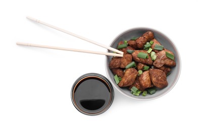 Tasty soy sauce, chopsticks and roasted meat isolated on white, top view