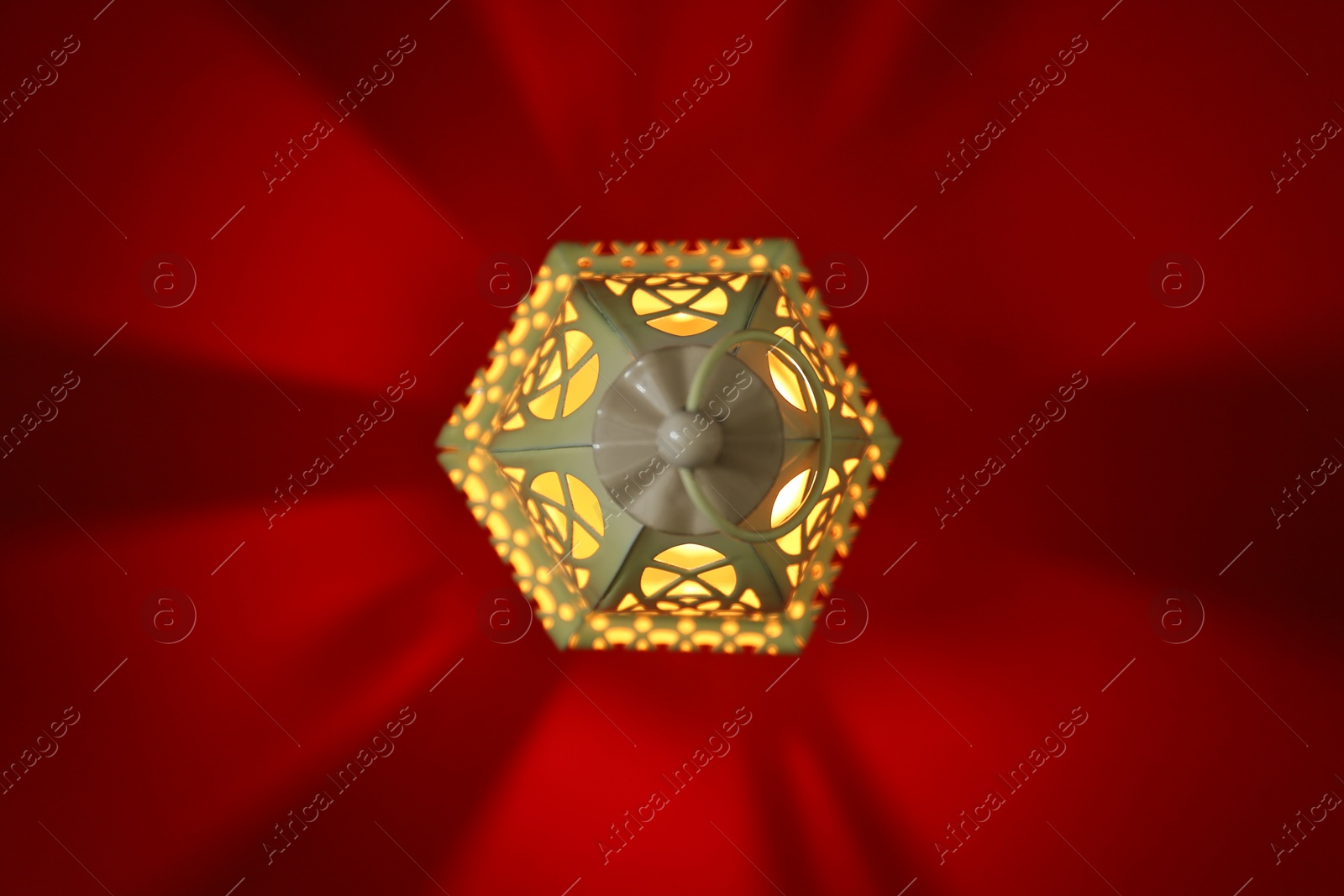 Photo of Decorative Arabic lantern on red background, top view