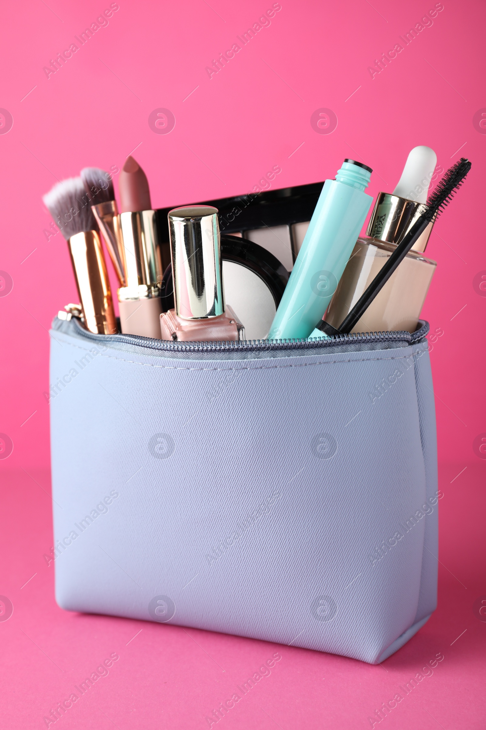 Photo of Cosmetic bag with makeup products and accessories on pink background