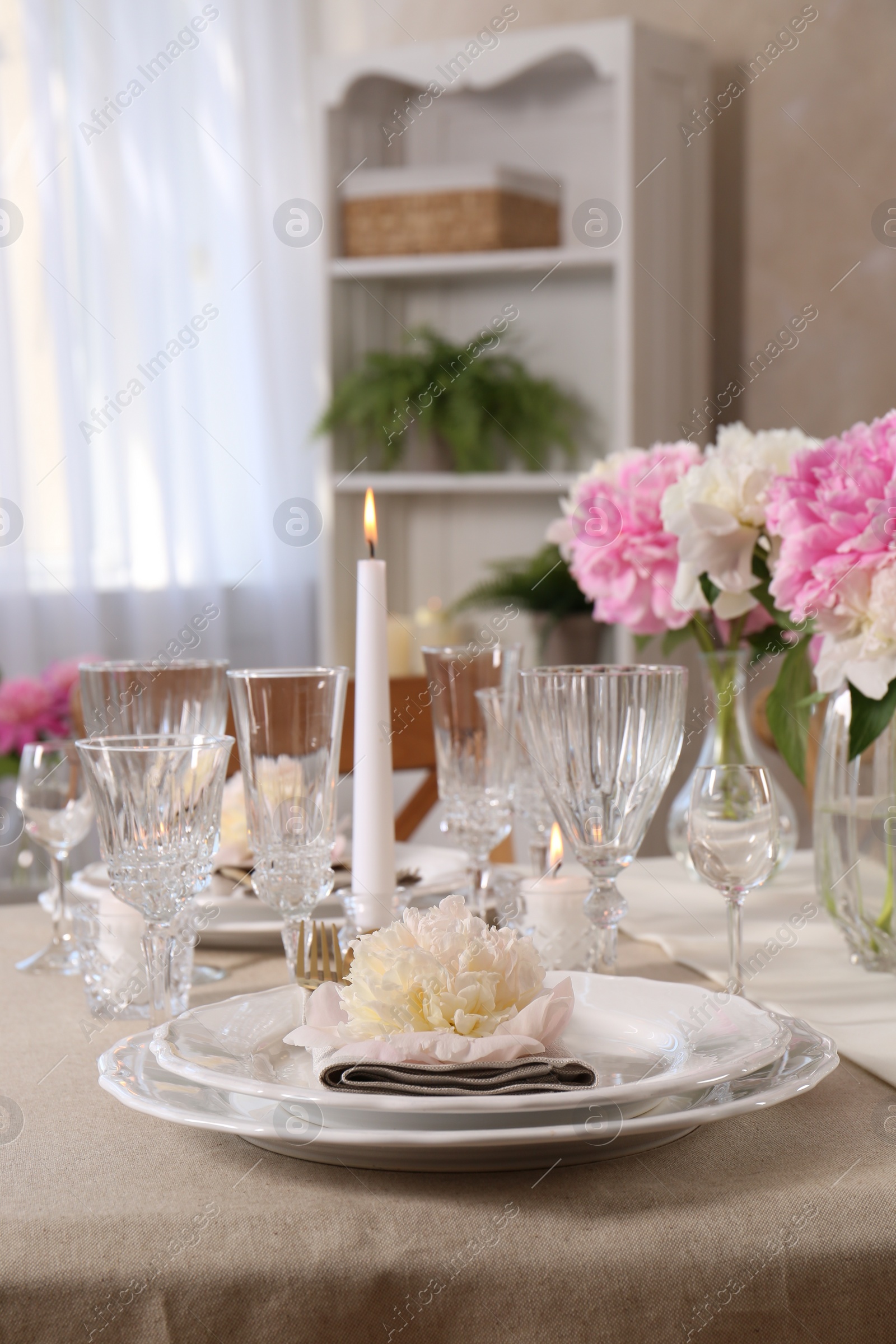 Photo of Stylish table setting with beautiful peonies and burning candles indoors