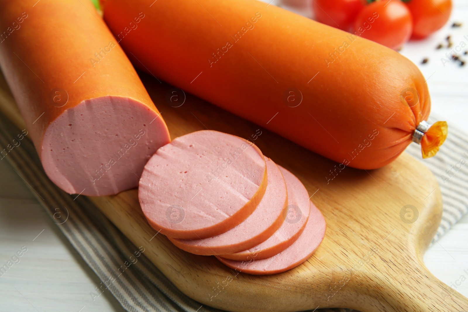 Photo of Board with tasty boiled sausages on white wooden table, closeup