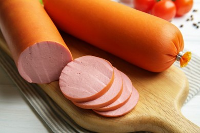 Photo of Board with tasty boiled sausages on white wooden table, closeup