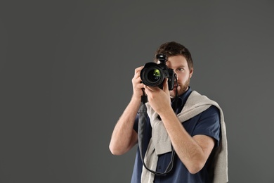 Man with camera and space for text on gray background. Professional photo studio