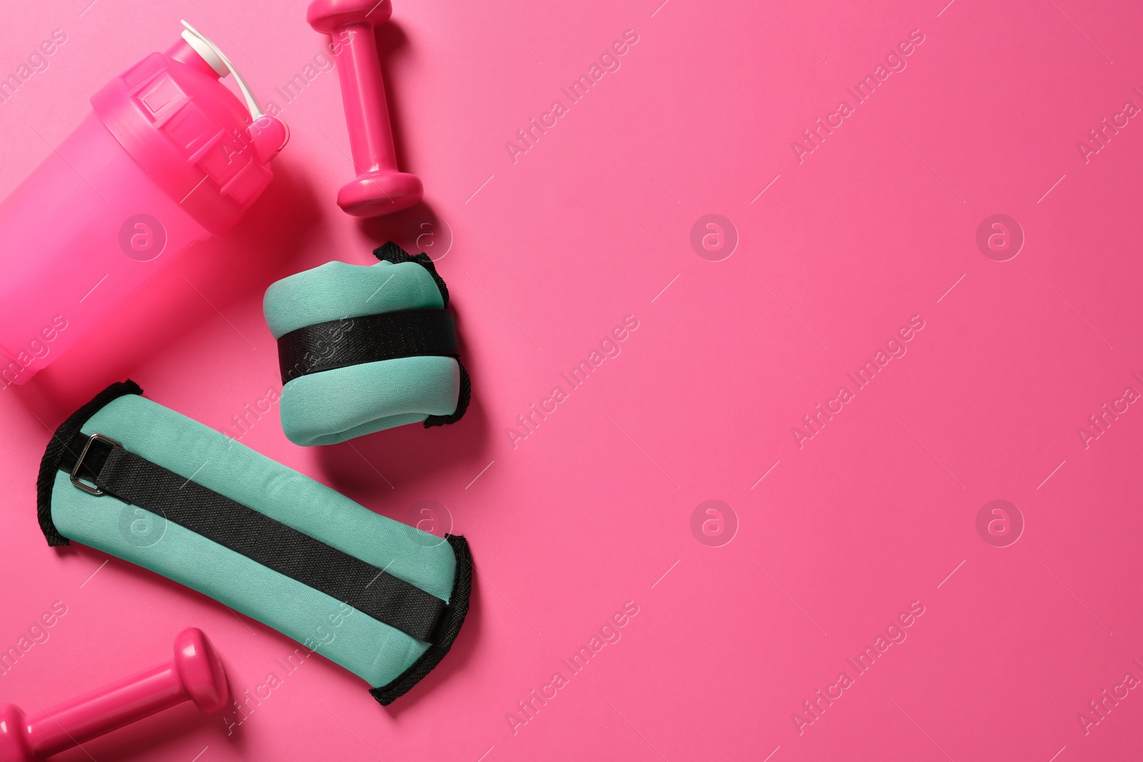 Photo of Turquoise weighting agents, dumbbells and shaker on pink background, flat lay. Space for text