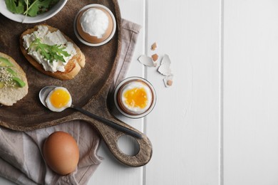 Breakfast with soft boiled eggs served on white wooden table, flat lay. Space for text