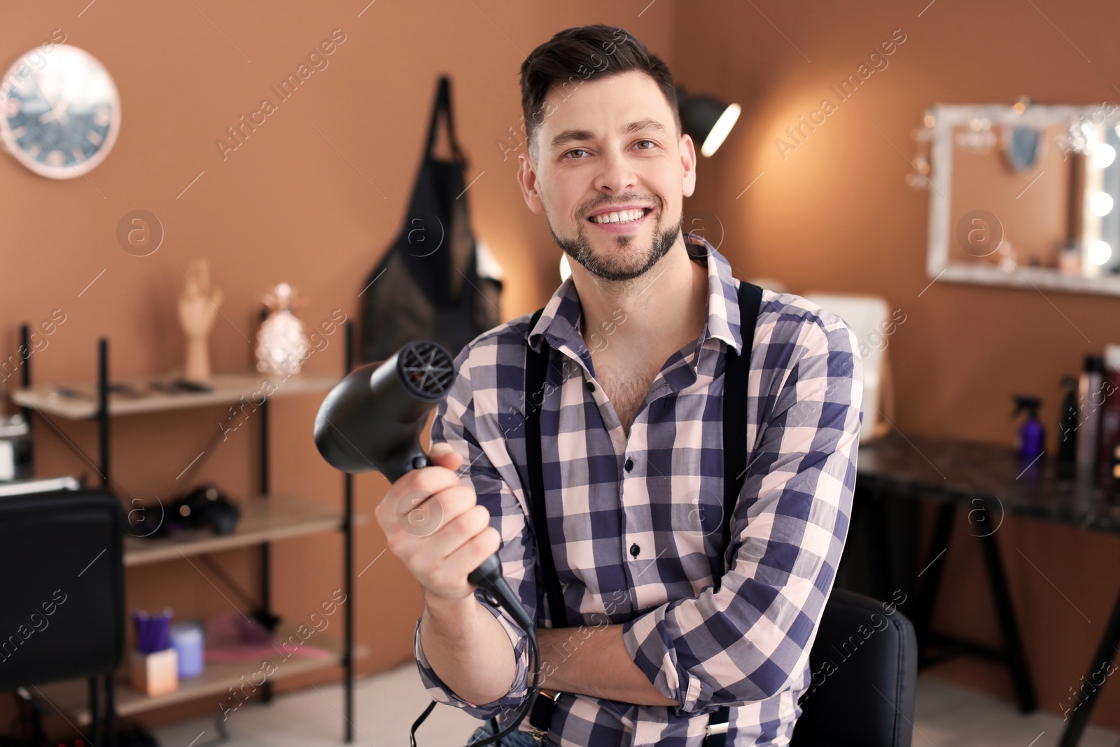 Photo of Professional hairdresser with blow dryer in beauty salon