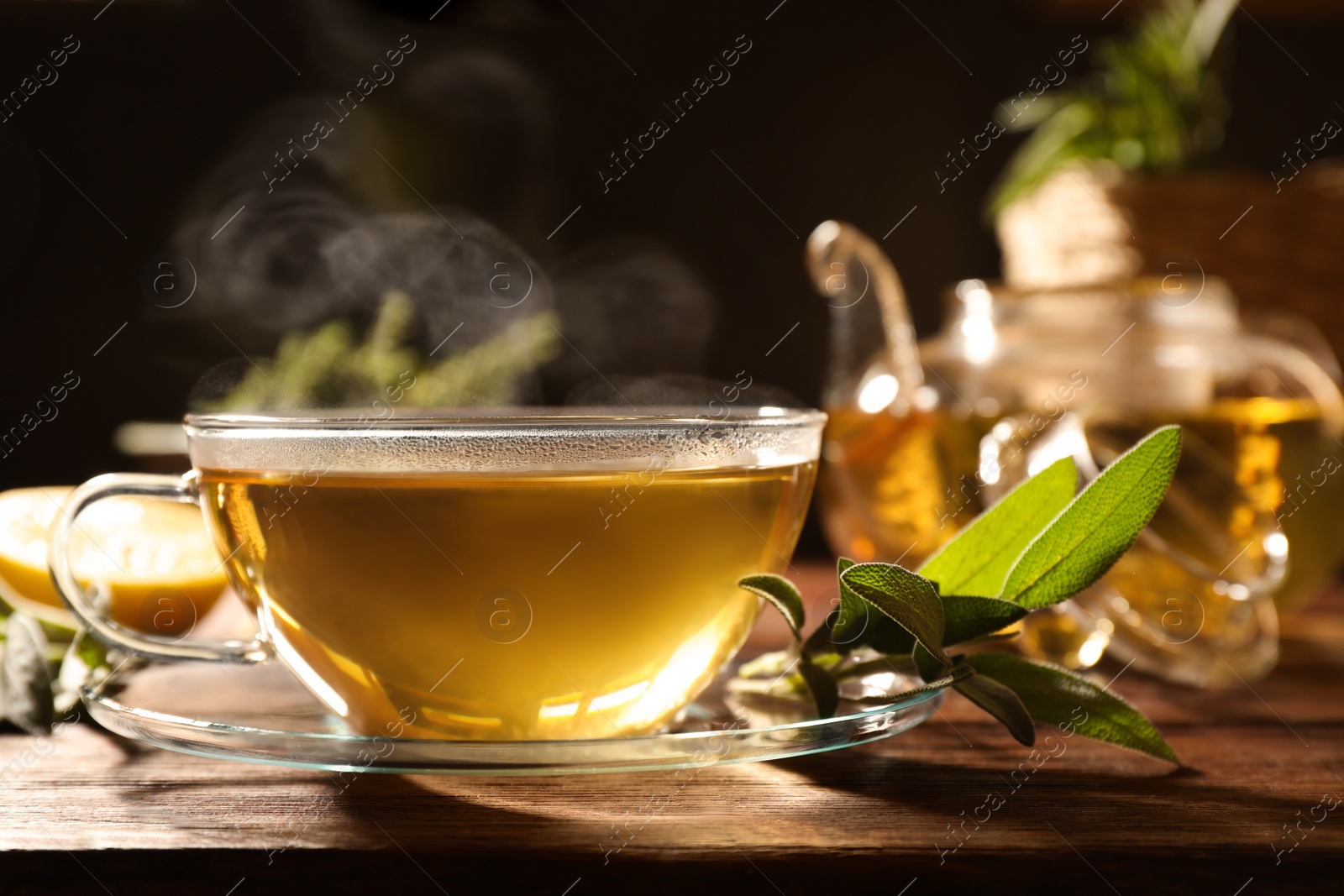 Photo of Cup of aromatic herbal tea and fresh sage on wooden table