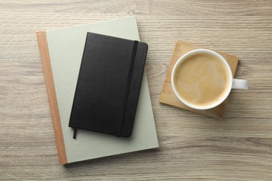 Photo of Different notebooks and cup of coffee on wooden table, flat lay