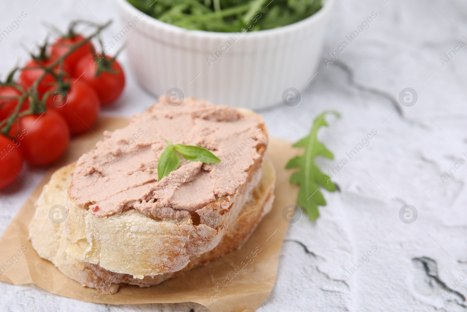 Photo of Delicious liverwurst sandwich with basil on white textured table, closeup. Space for text