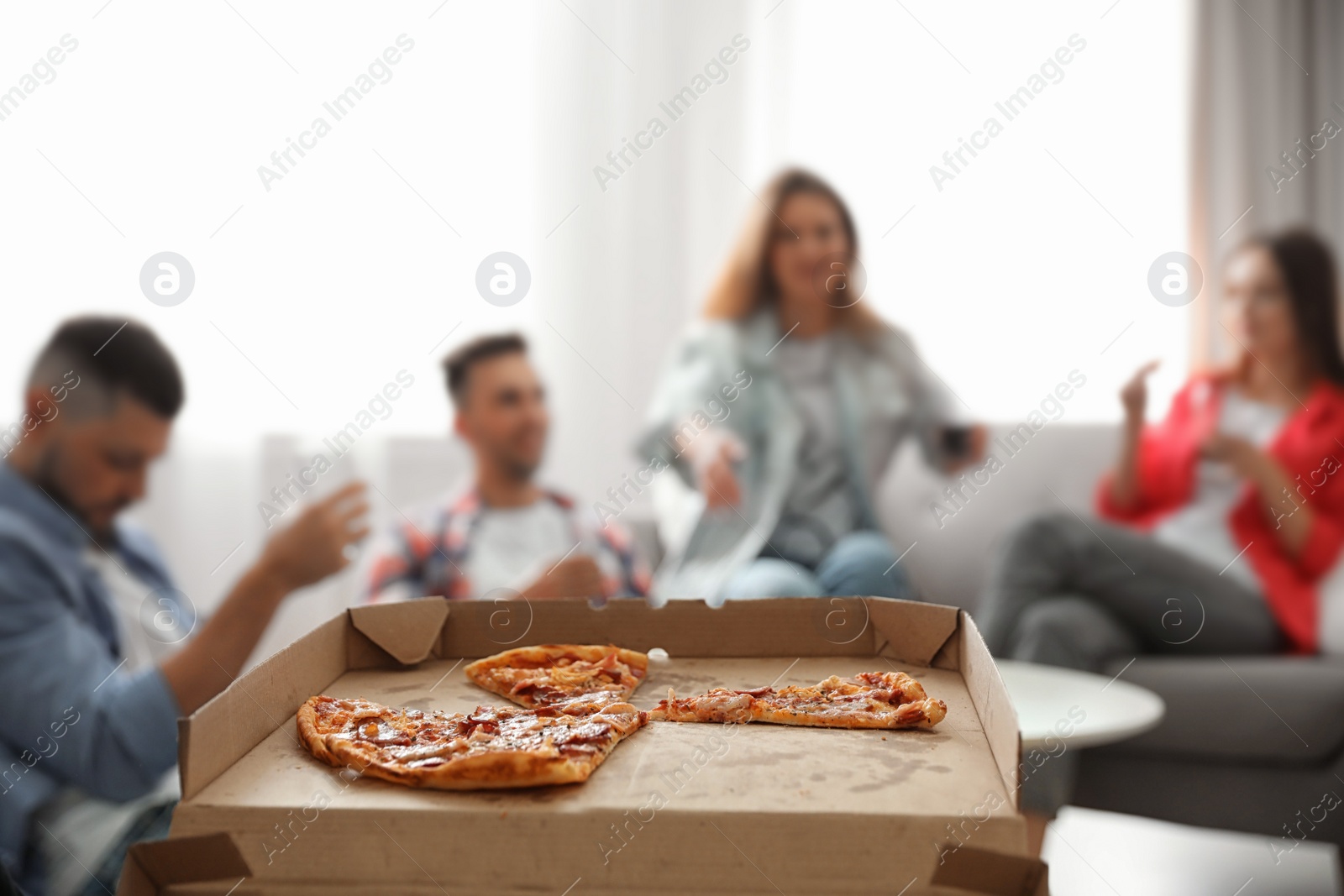 Photo of Group of friends having party at home, focus on pizza