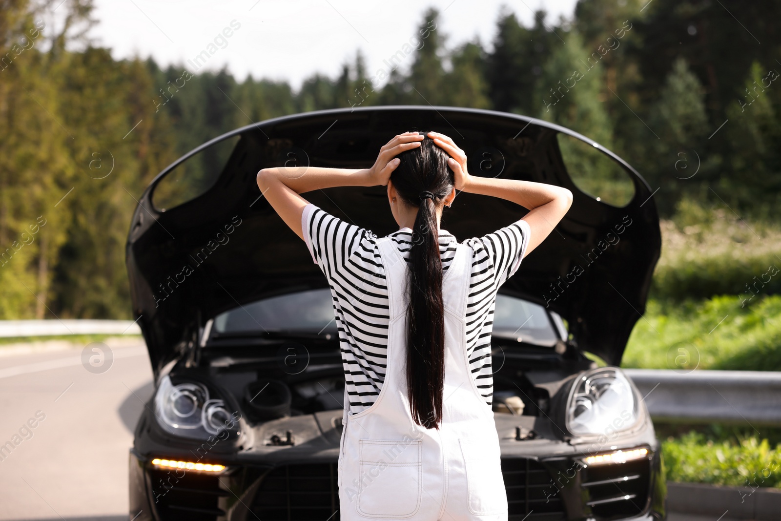 Photo of Woman near broken car outdoors, back view