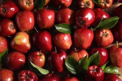 Fresh ripe red apples with leaves on wooden table, flat lay